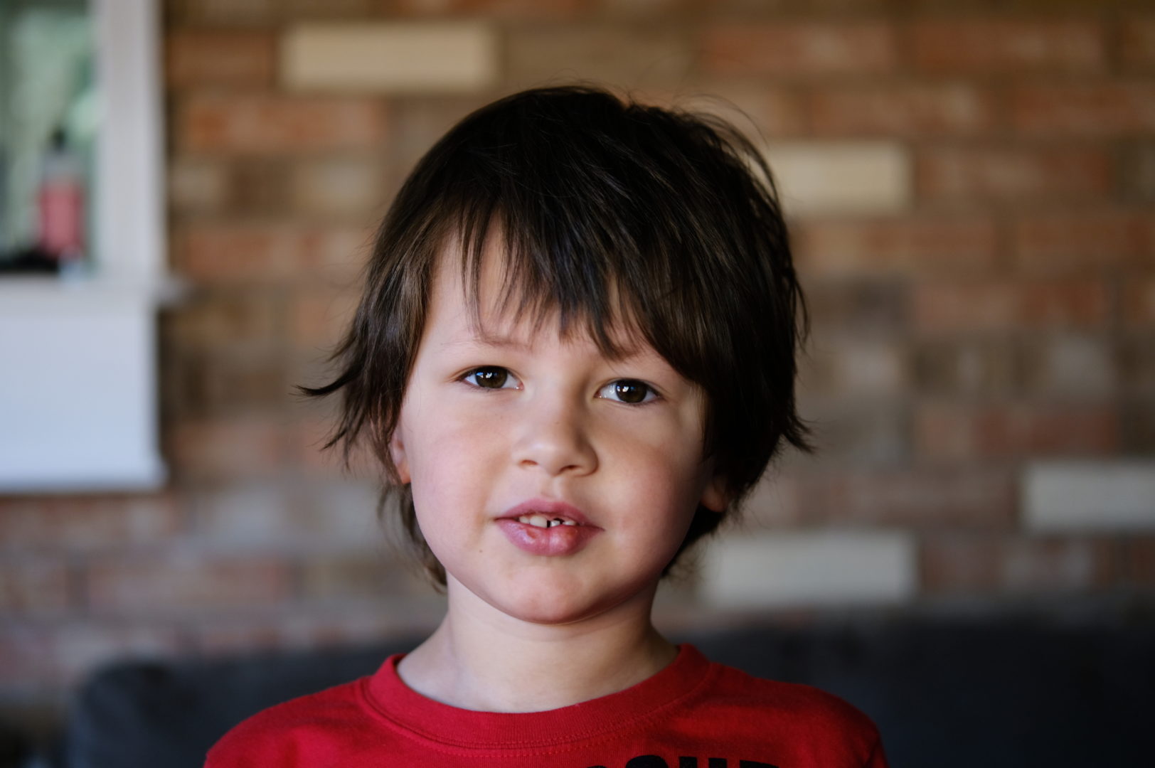 A 5 year old boy with scraggly hair looks at the camera.