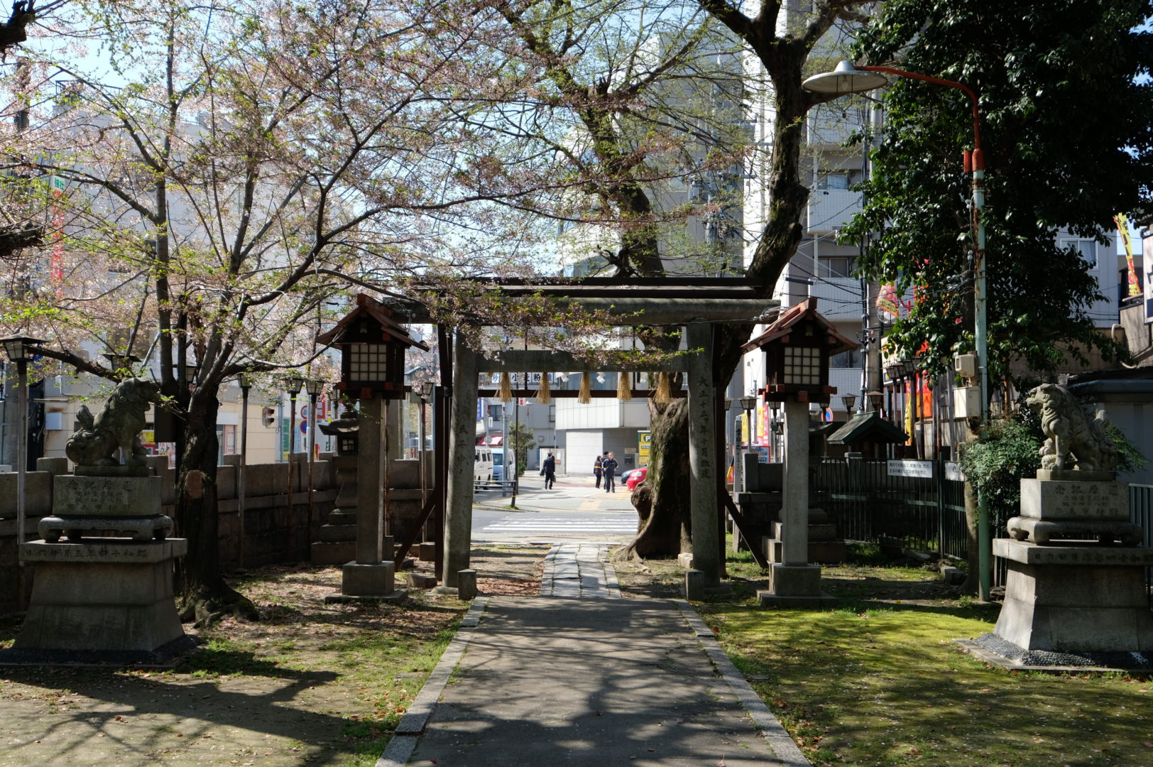 A street is framed by a gate that is the entrance of a shrine in downtown Nagoya, Japan.