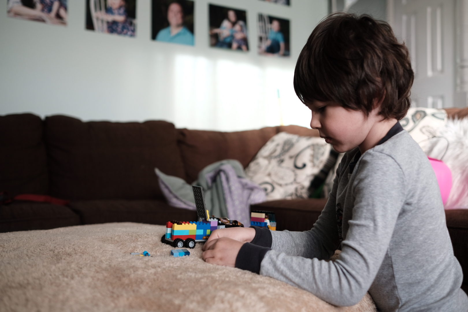 A little boy plays with his LEGOs on a blanket. 