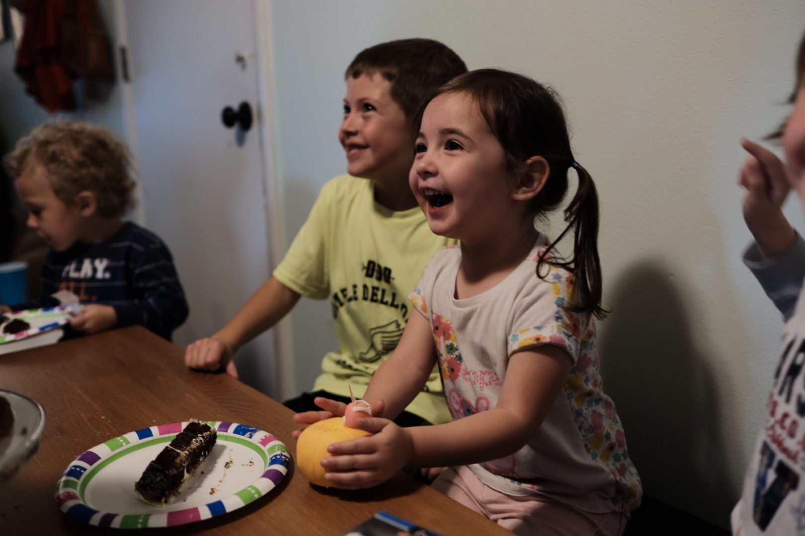 A little girl smiles while looking at her birthday cake (out of frame)
