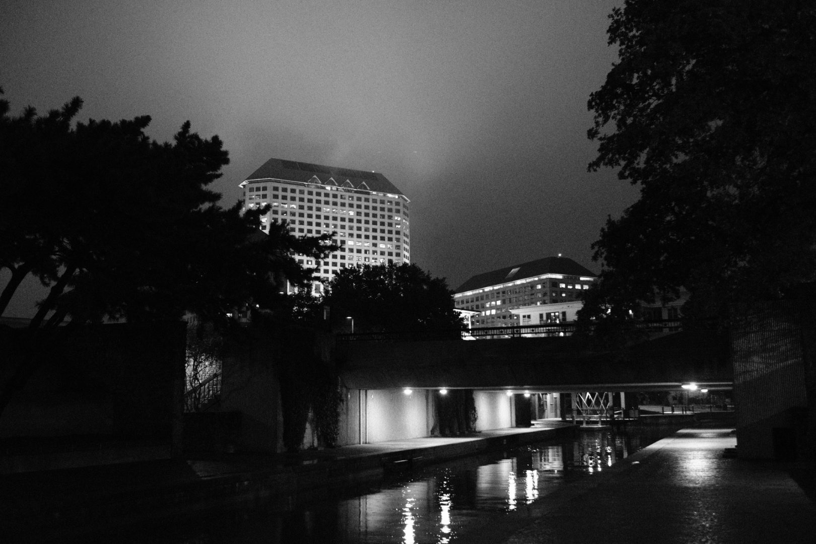 A B&W photo of a water way and Dallas in the dark.