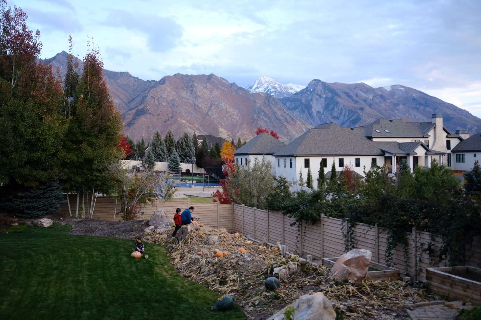 A panoramic view of Alpine and Utah County with a snow capped Mt. Timpanogos in the distance and a family in a pumpkin patch in the foreground.