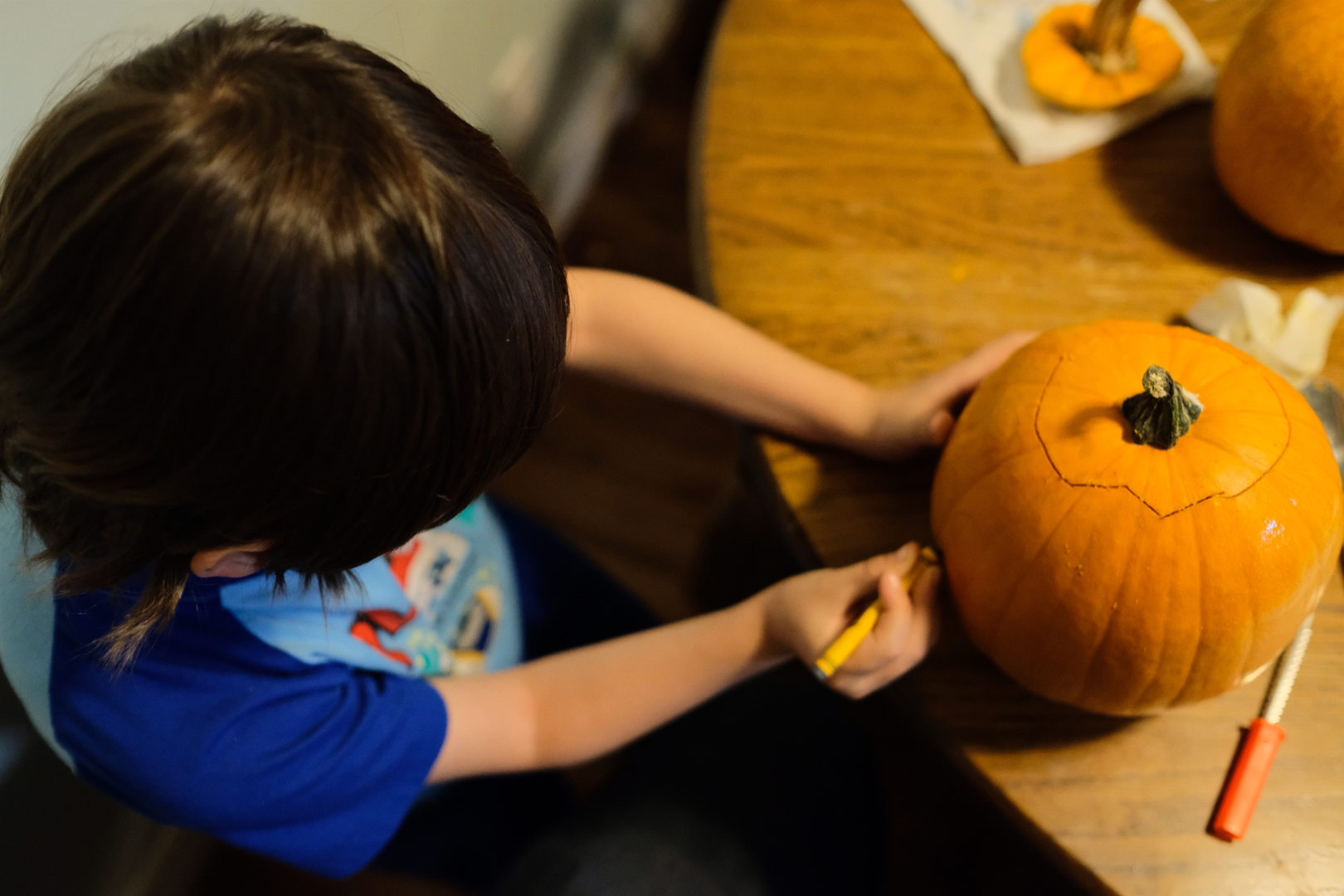 Emmett draws the eyes on his pumpkin