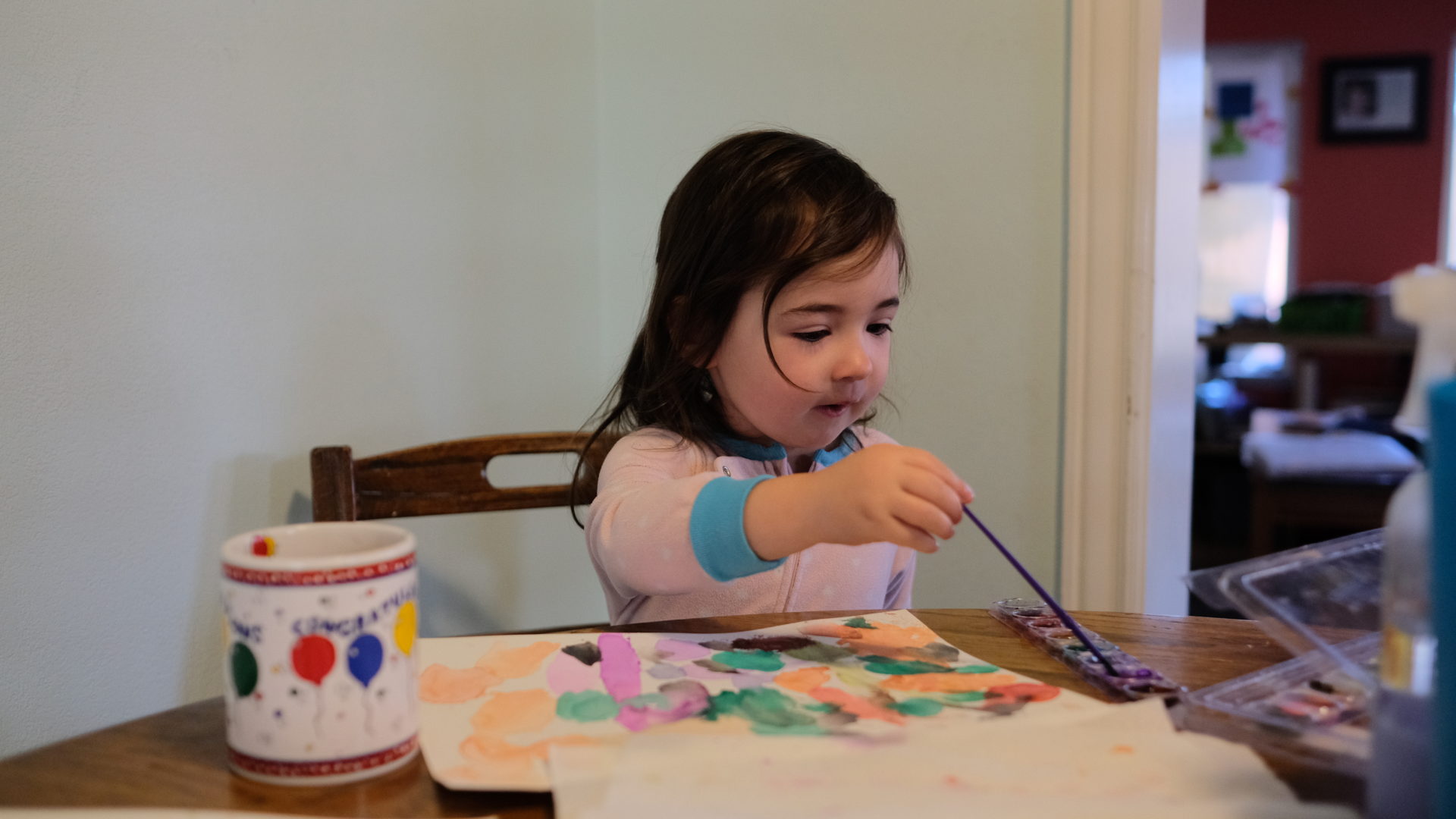 Elle paints with her watercolors at the kitchen table.