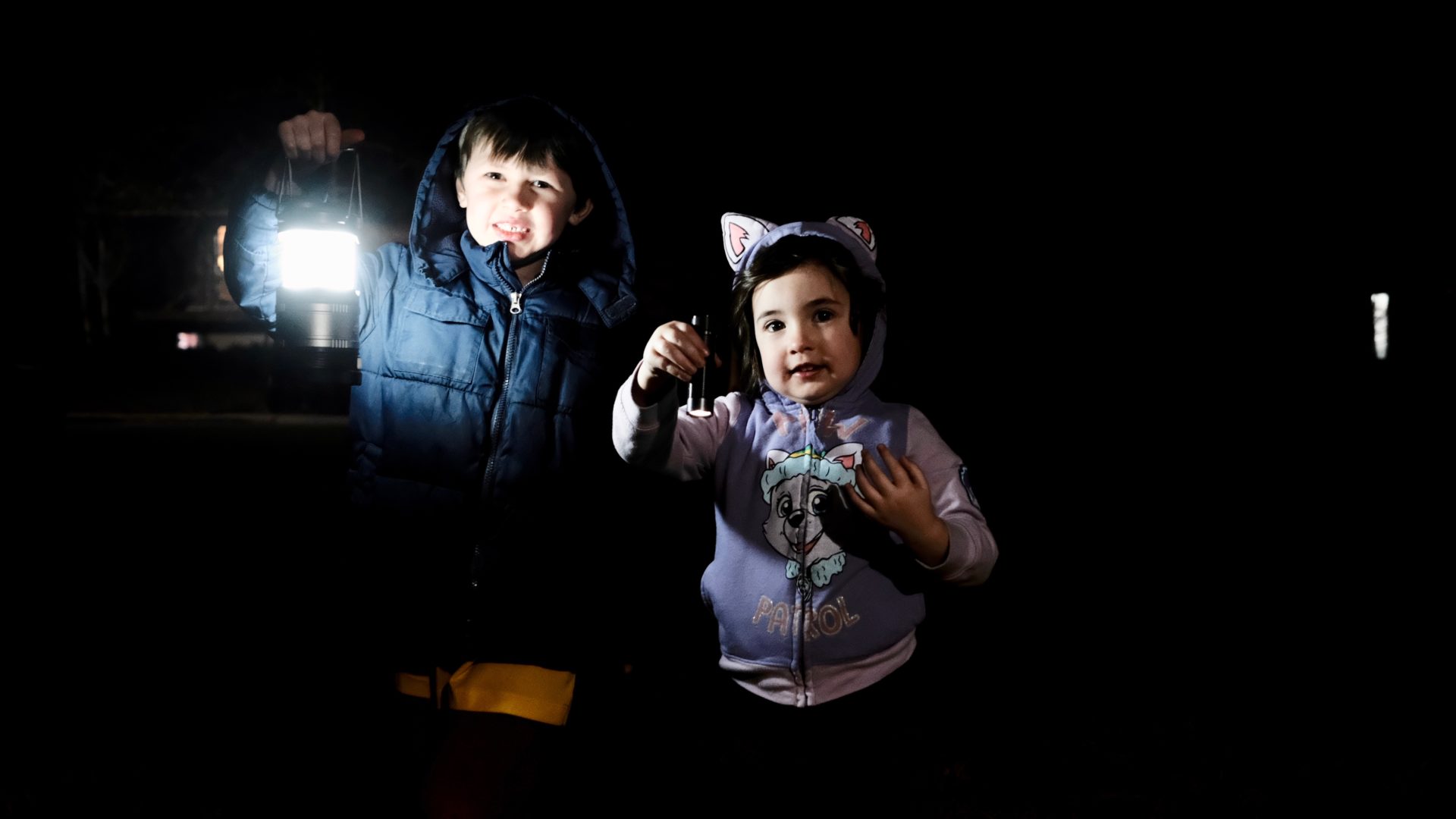 Emmett holding a lantern, Elle holding a flashlight.