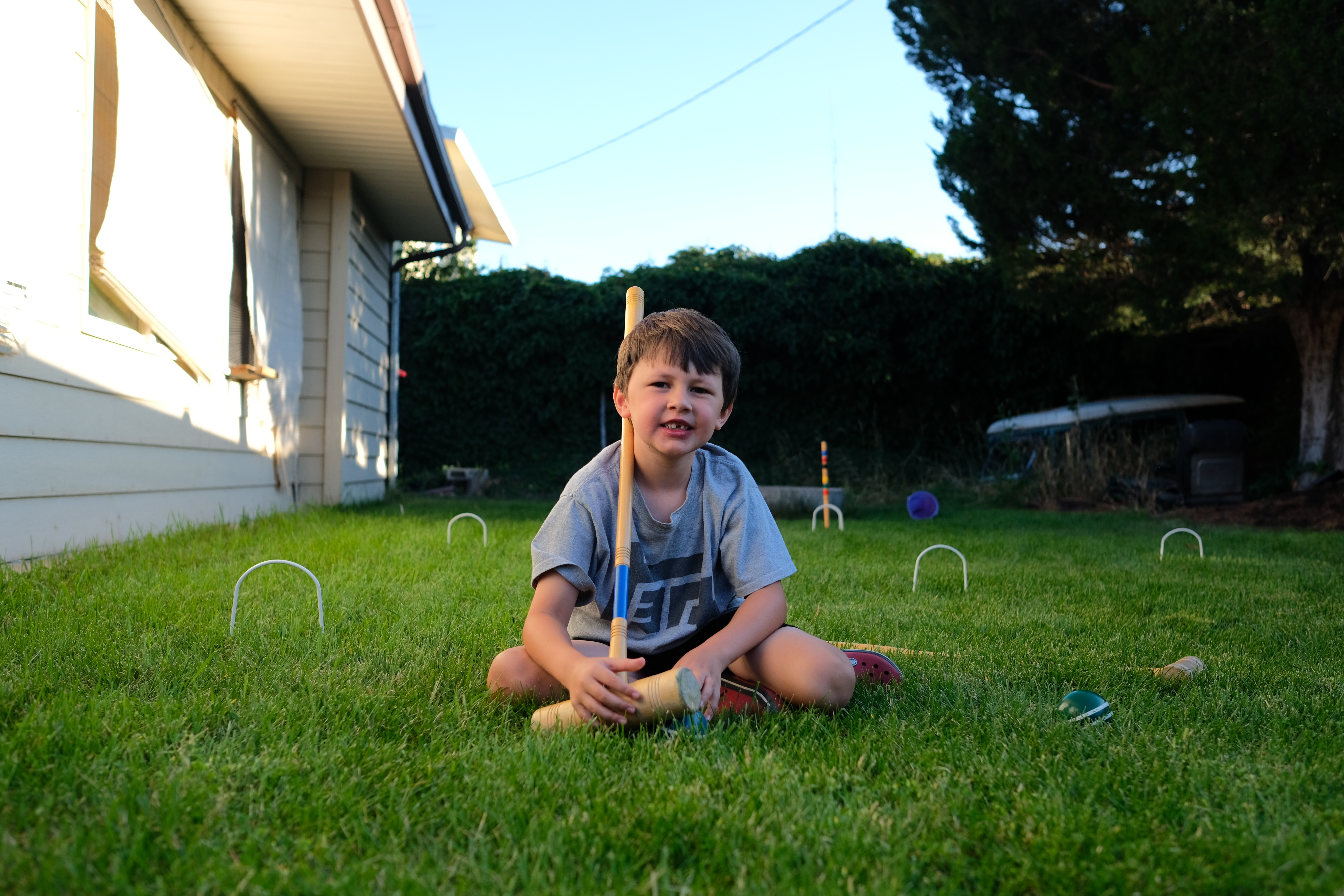 Emmett sitting on the grass holding a croquet mallet